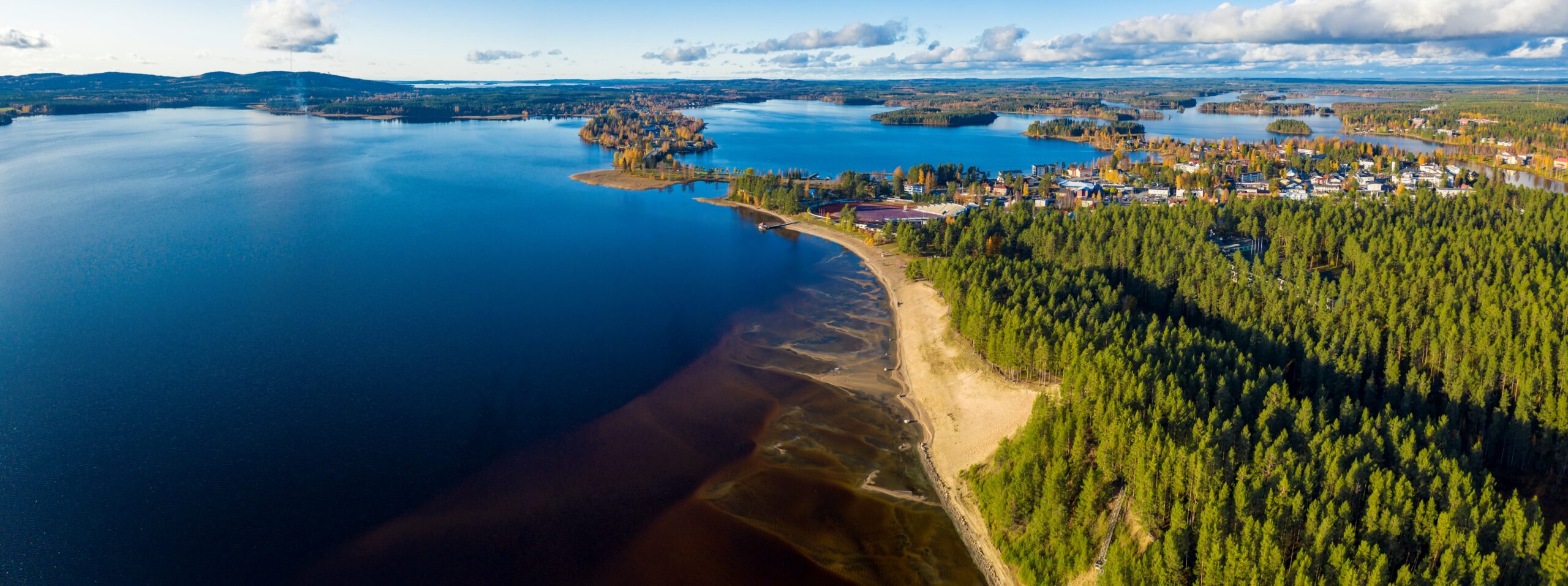 Ilmasta otettu panoraamakuva Sotkamosta. Kuvassa näkyy sininen Sapsojärvi, Hiukan uimarannan hiekat sekä mäntymetsä.